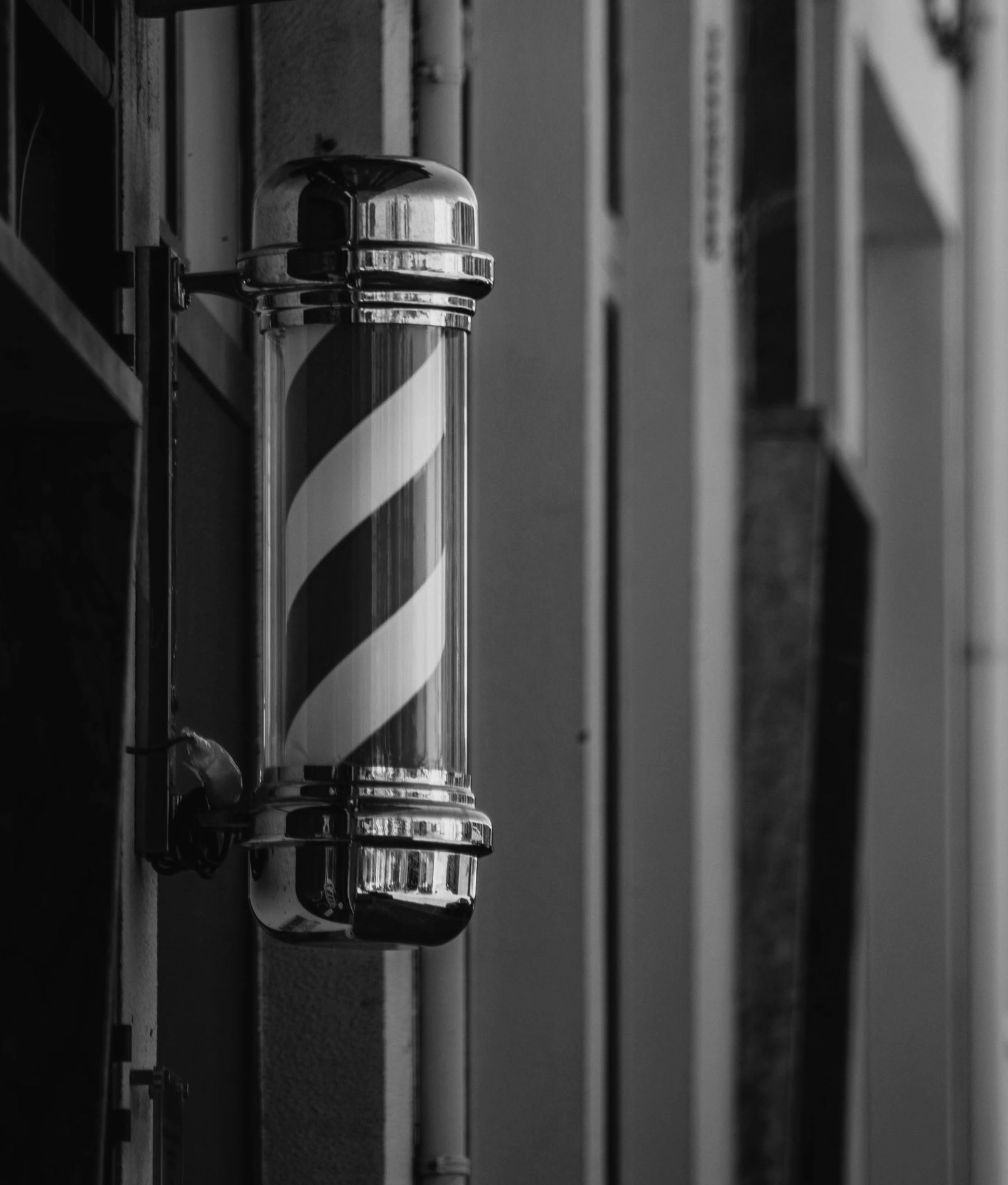 Barber pole with red and white stripes, hanging outside a building.