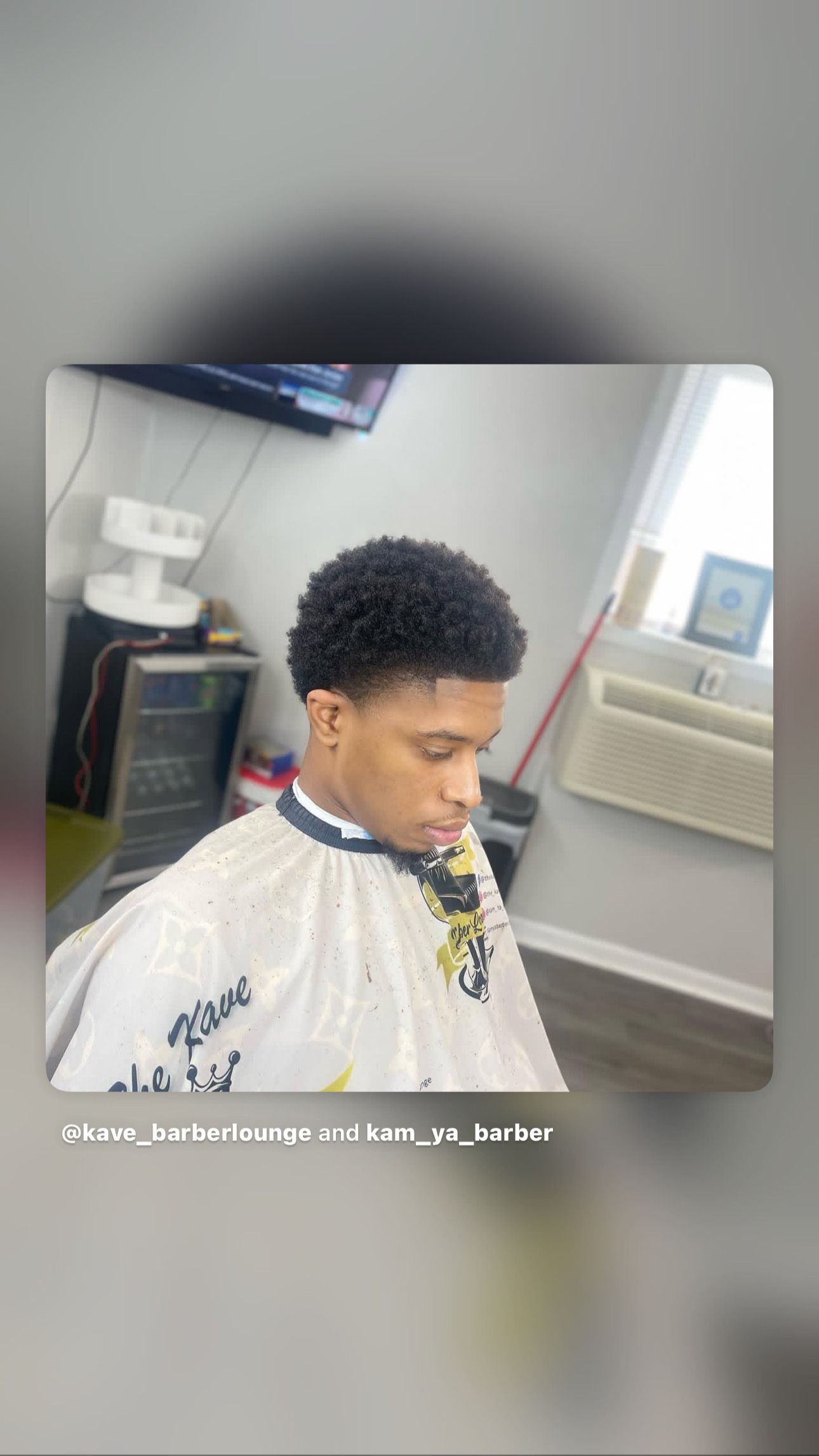 Man with a fresh haircut at a barber shop, wearing a cape.