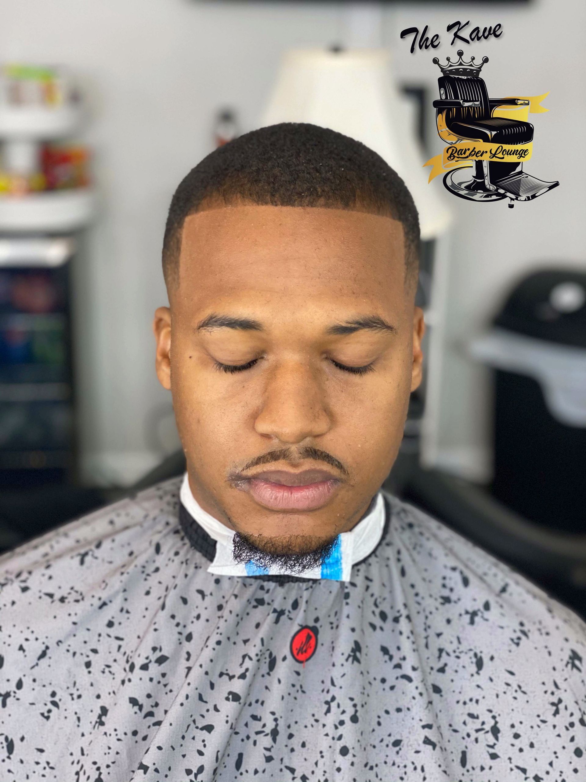 Man with closed eyes, fresh haircut, wearing barber cape.