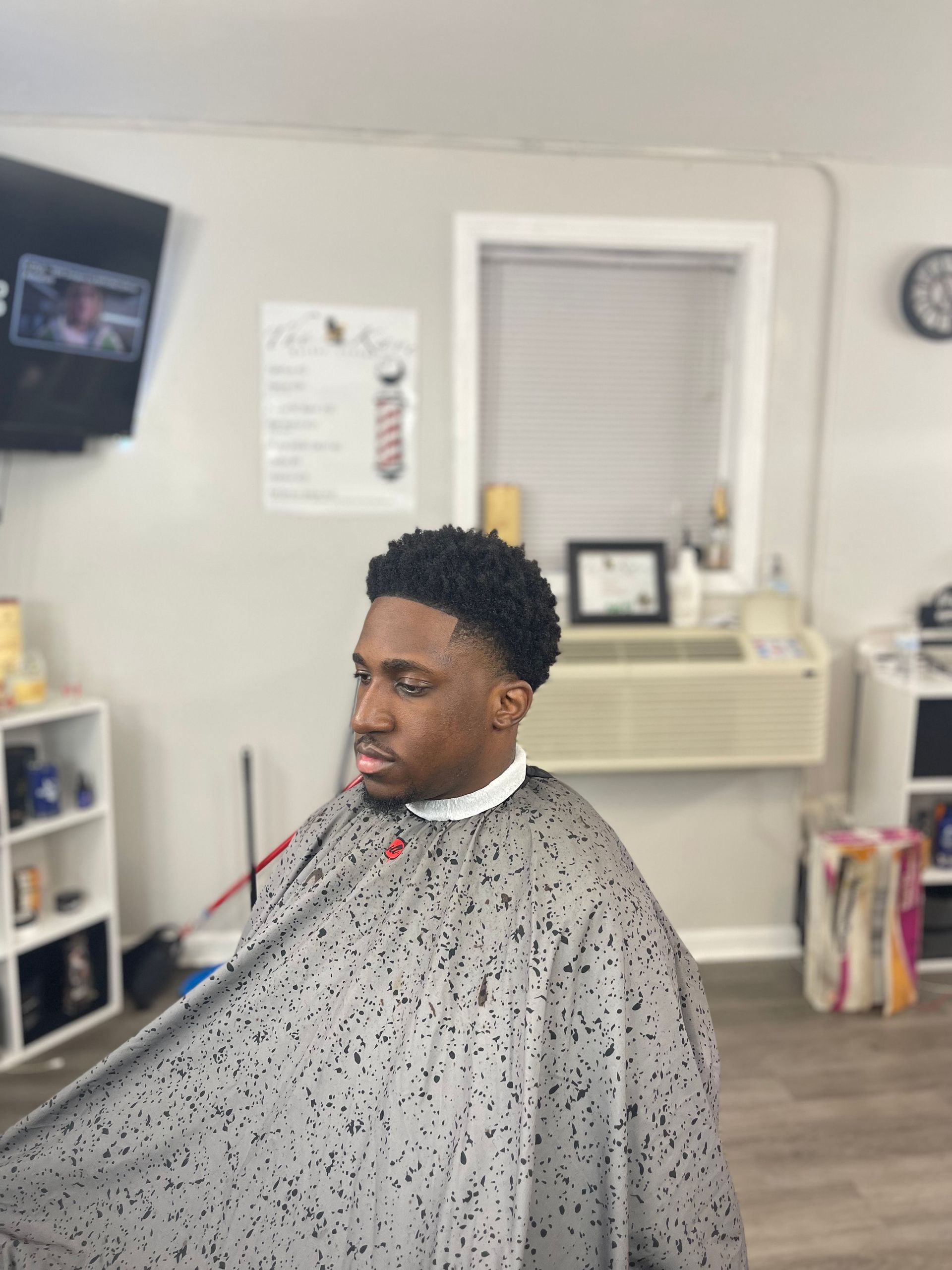 Man in barber cape with fresh haircut at a barbershop.