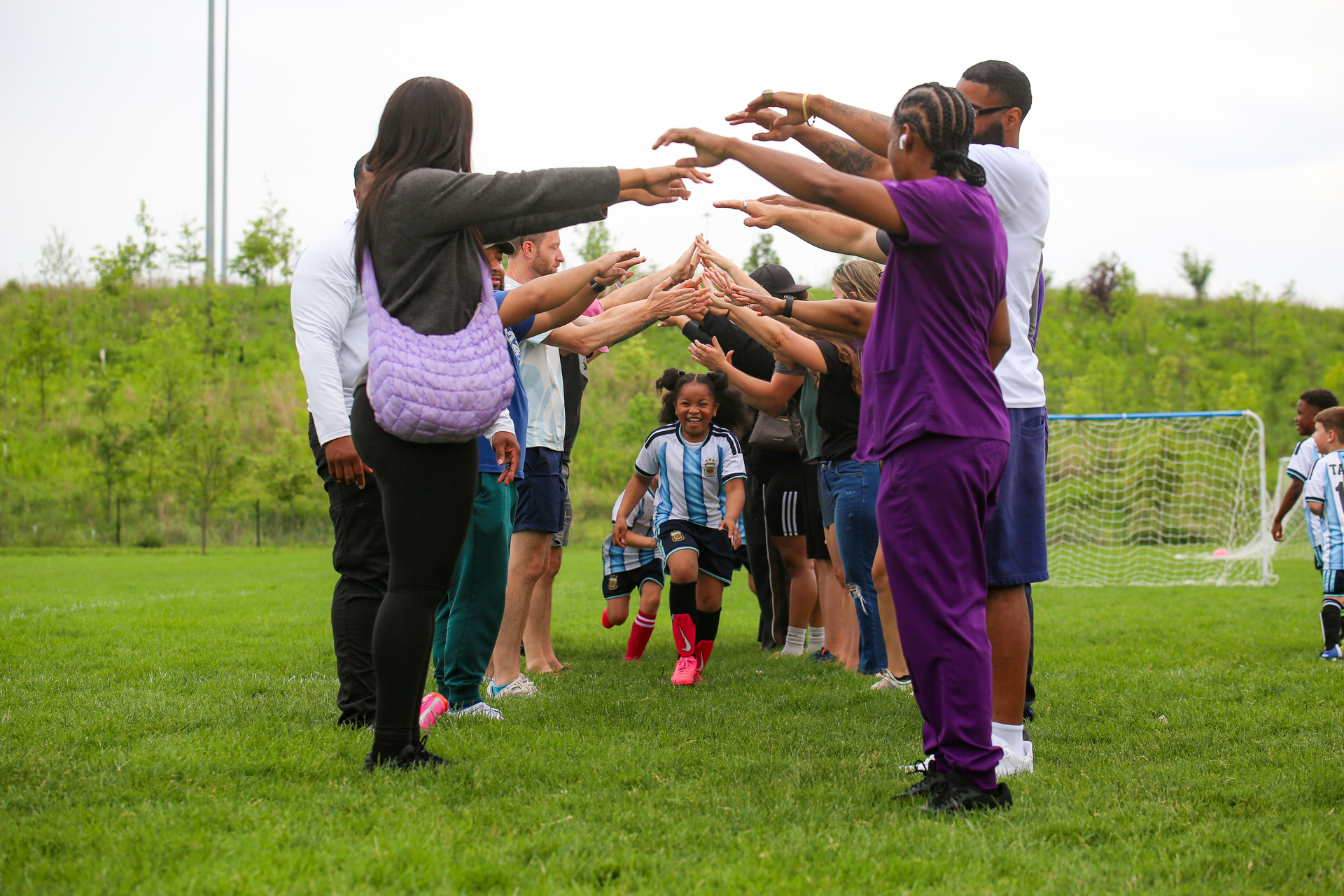People arranging sports equipment on a grassy field near cones and buckets during an outdoor activity