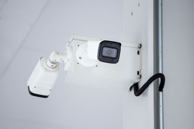 Two white security cameras mounted on a wall junction box.
