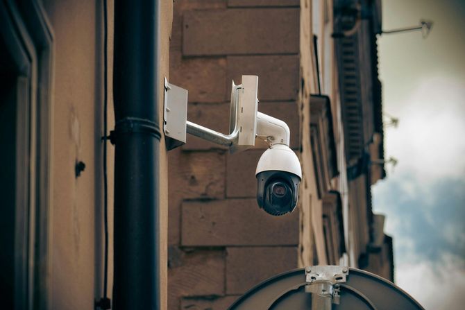 A white dome security camera mounted on a stone building wall.
