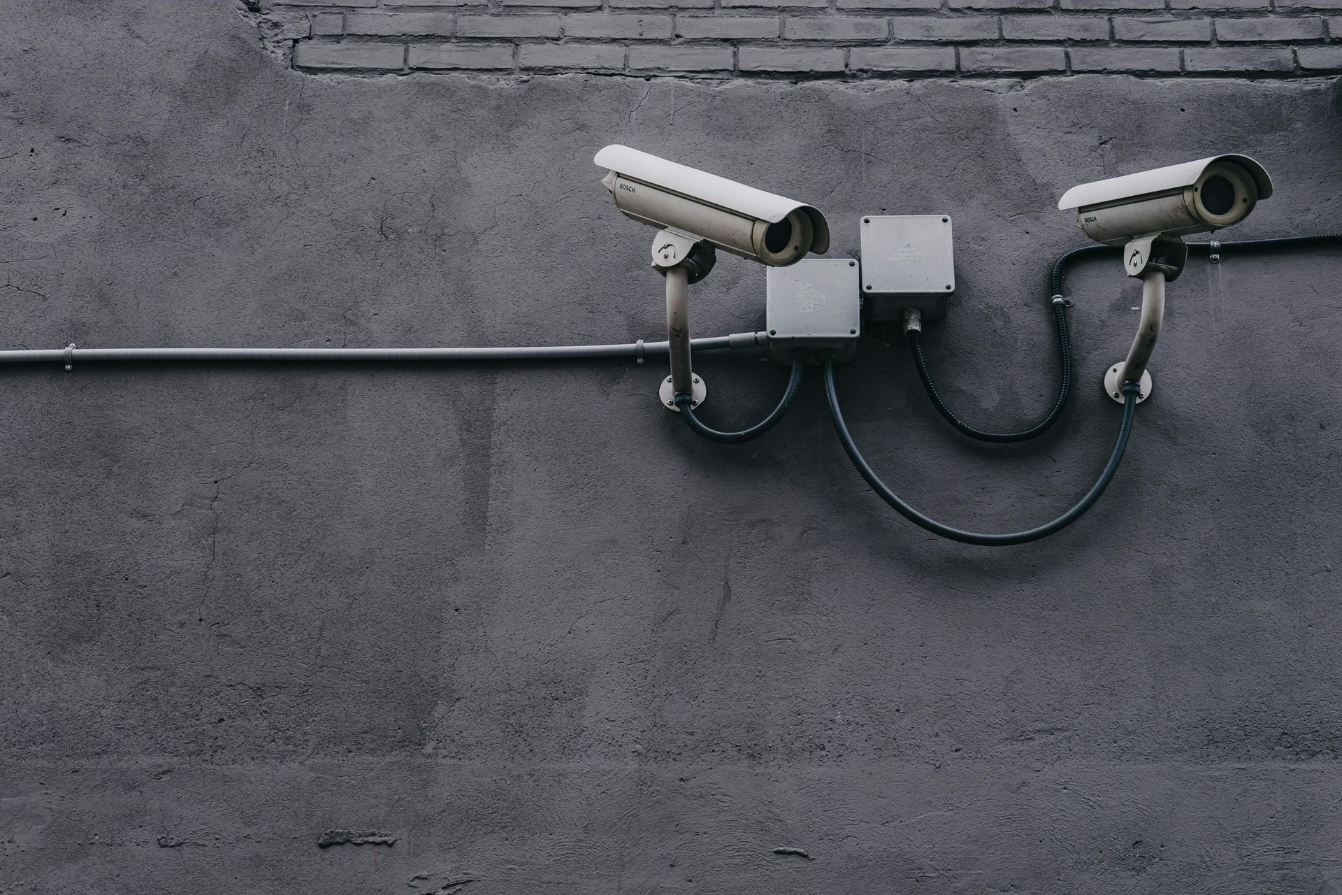 Two cameras mounted on a white textured concrete wall.