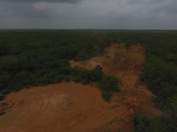 An aerial view of a dirt road in the middle of a forest.