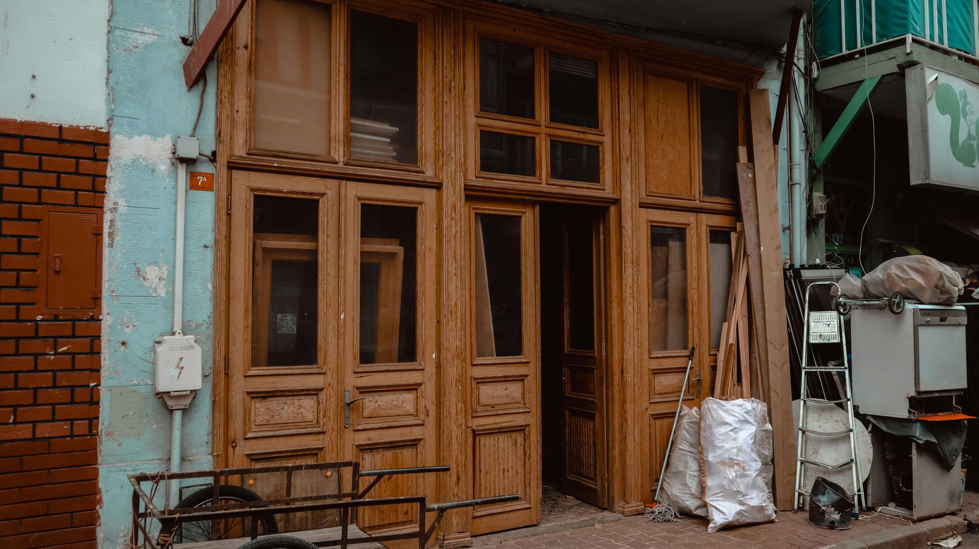 Weathered wooden storefront with multiple doors and windows, blue and brick wall.