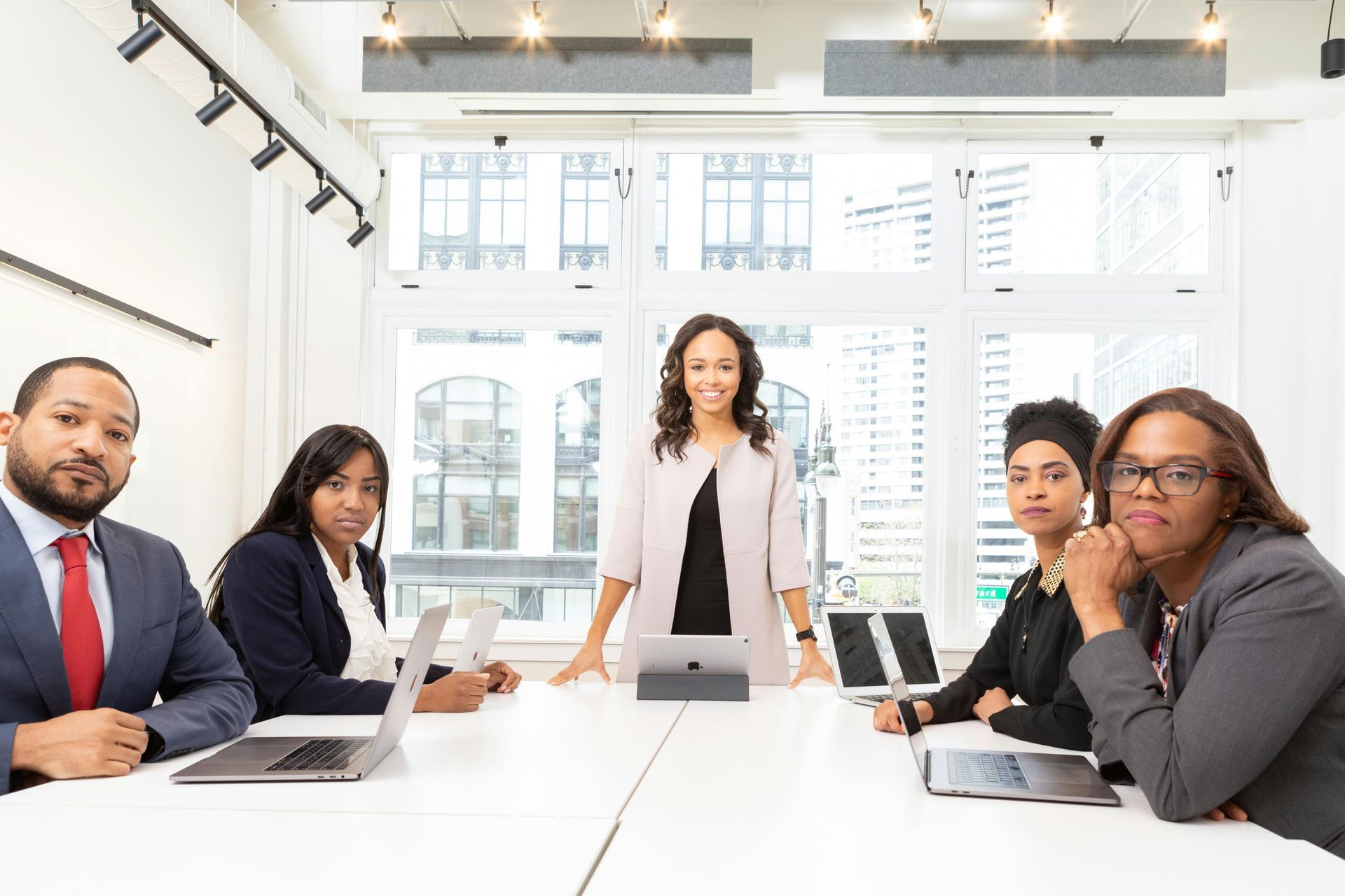 Business team at a white table in a conference room, smiling at the camera.