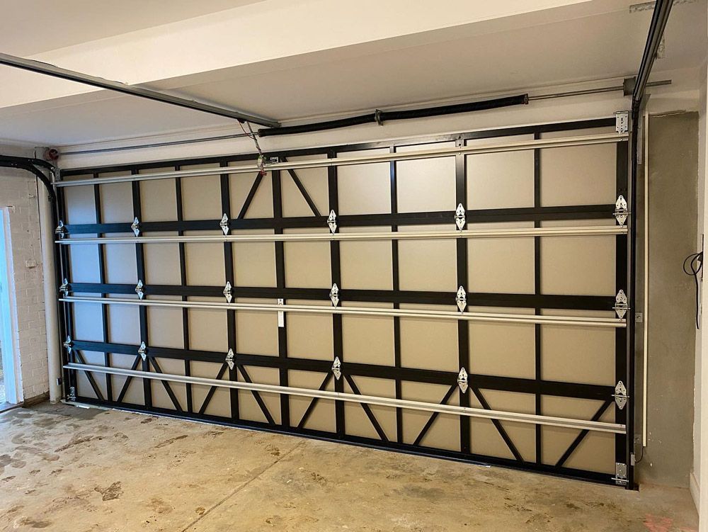 Garage door: white panels, black frame, metal tracks, concrete floor, interior view.