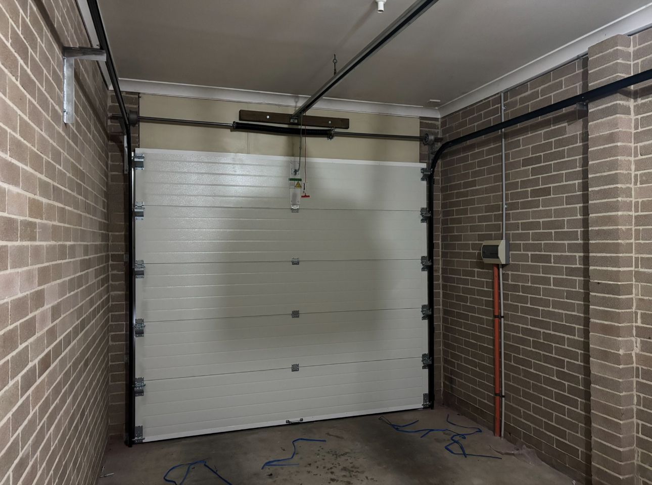 Brown garage door on a brick and tan building with a cloudy sky overhead.
