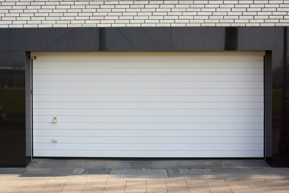 Brown garage door partially open in a brick structure.