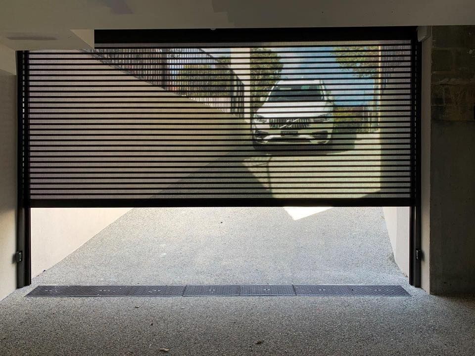 Sliding glass door with partially drawn roller shutters, indoor setting with a pool table and a chair on a balcony.