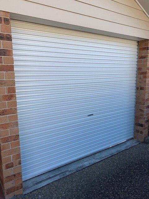 White metal roller garage door closed, between brick pillars.