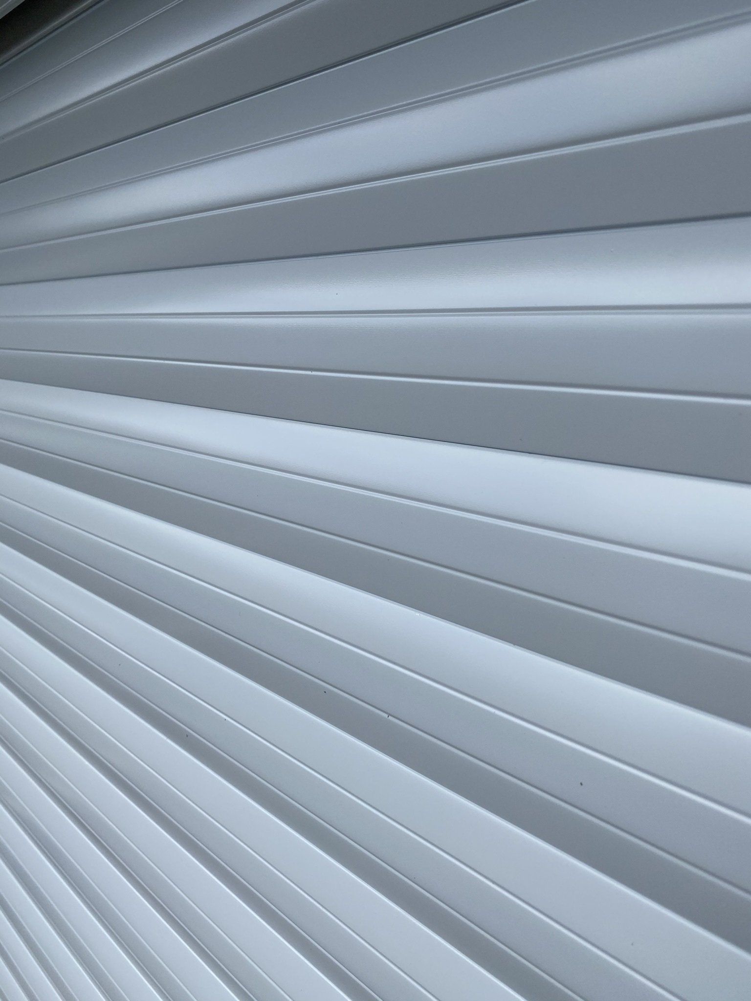 White, slatted surface angled diagonally. Parallel lines recede, suggesting texture and depth.