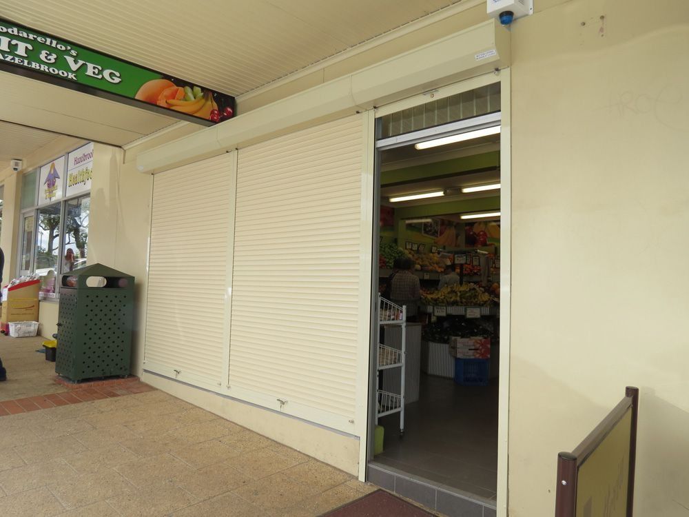 Fruit and Veg shop with closed security shutter and partially open doorway.