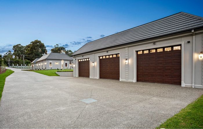 Three-car garage with brown doors, light-colored walls, and a concrete driveway.