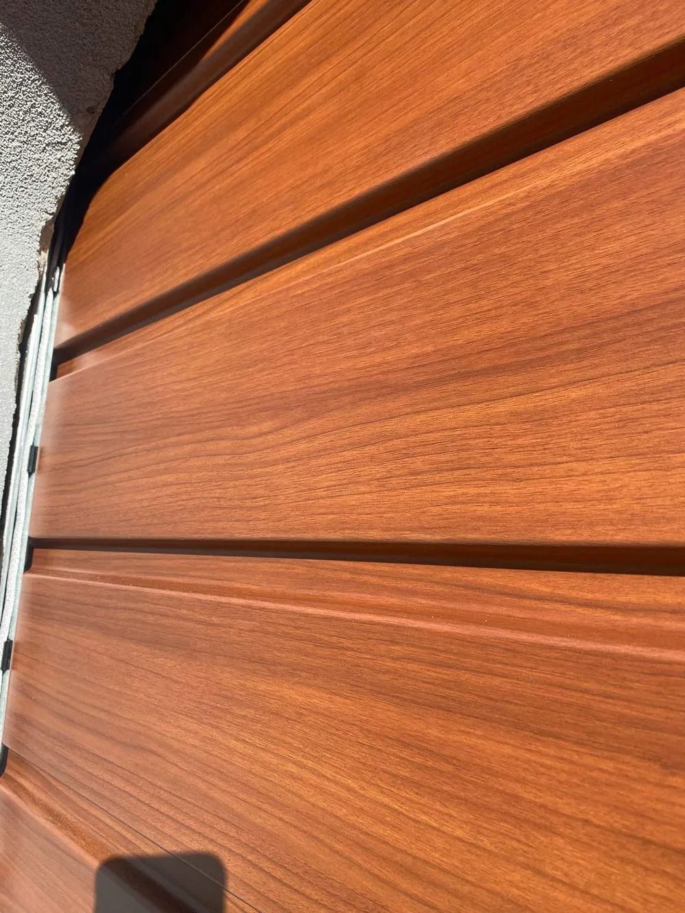 Close-up view of horizontal reddish-brown wood siding with grooves.
