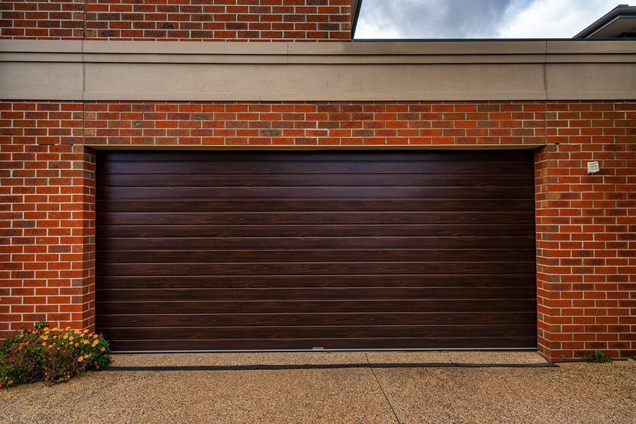 A modern brick house with a garage, front door, and a cloudy blue sky.