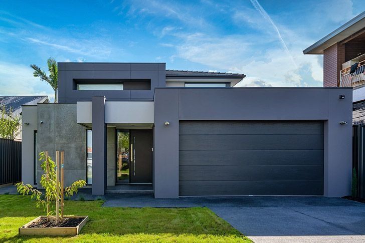 Two orange garage doors with white trim, driveway in front, and a house in the background.