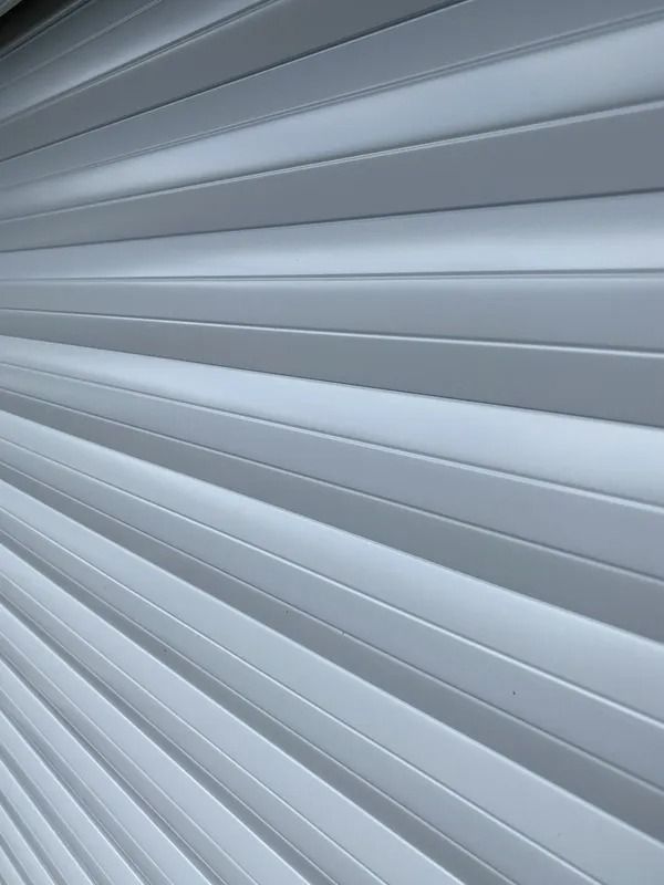 Gray, slatted surface; perspective view. Appears to be an exterior wall or rolling shutter.