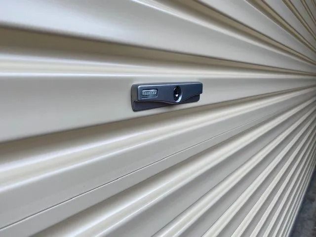 Wooden garage door with horizontal planks, medium brown hue. Building exterior, gravel driveway.