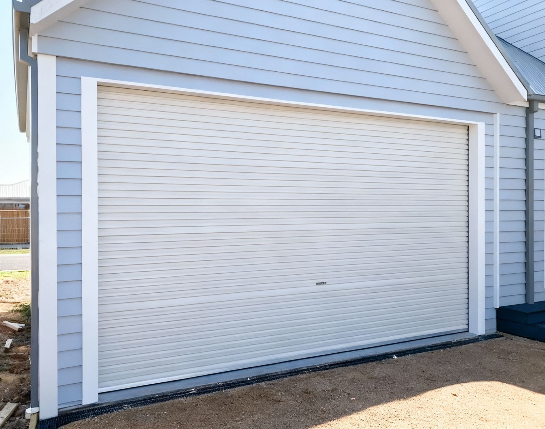 Driveway leading to a three-car garage with brown doors and outdoor lights.