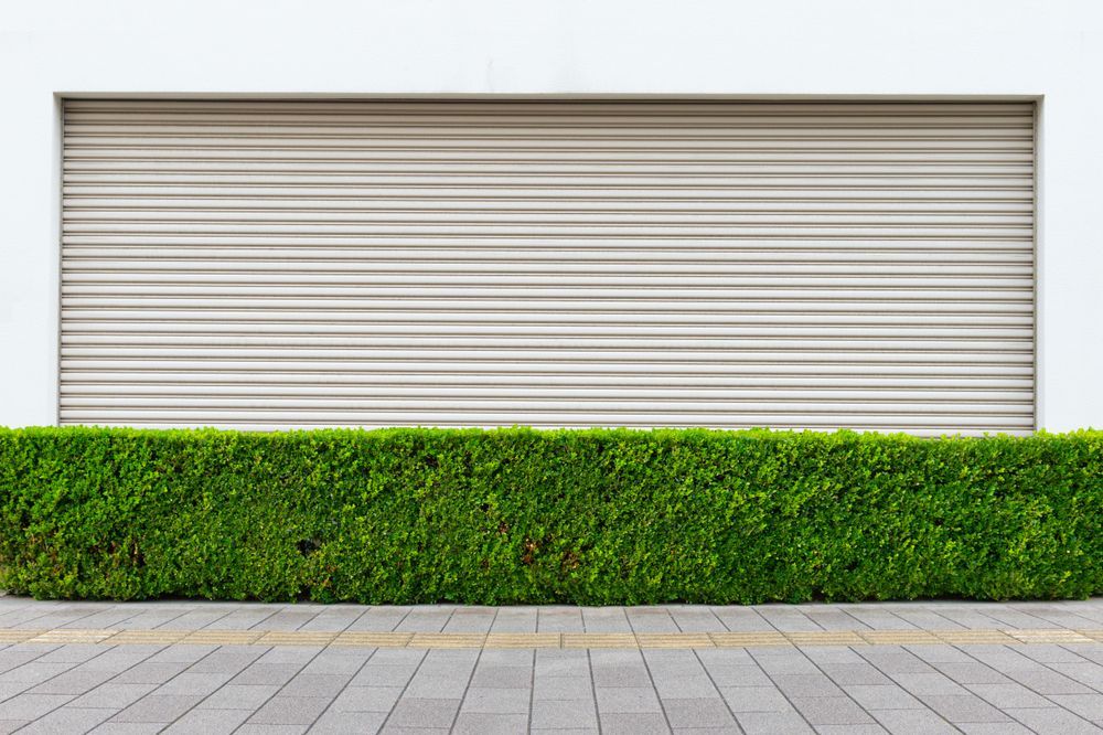 Two dark brown horizontal-slatted garage doors set in a brick building.
