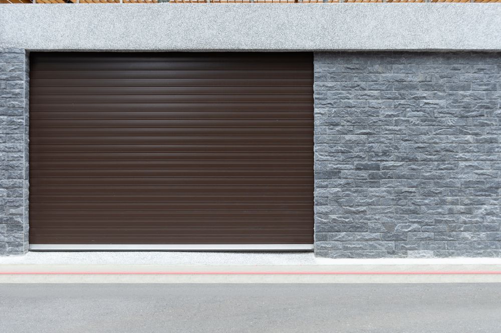 Two-story brick house with garage. A worker on a ladder paints the column under the porch, blue sky.
