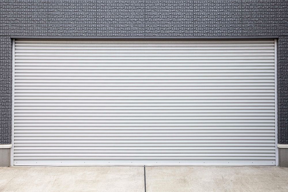 Two beige roller doors in a metal warehouse, with black and yellow bollards.