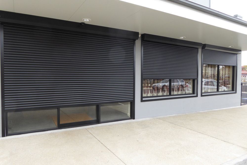 White, closed roll-up garage door with horizontal slats, set in a white frame, indoors, with a dark floor.