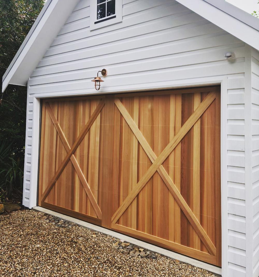 White garage door with rectangular window and white trim against a white brick wall.