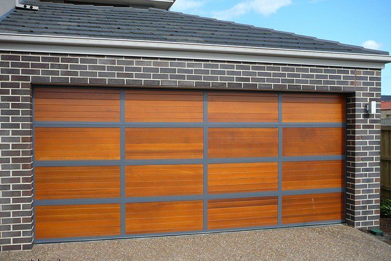 Garage door, silver metallic roll-up style, brick wall, sunny exterior.