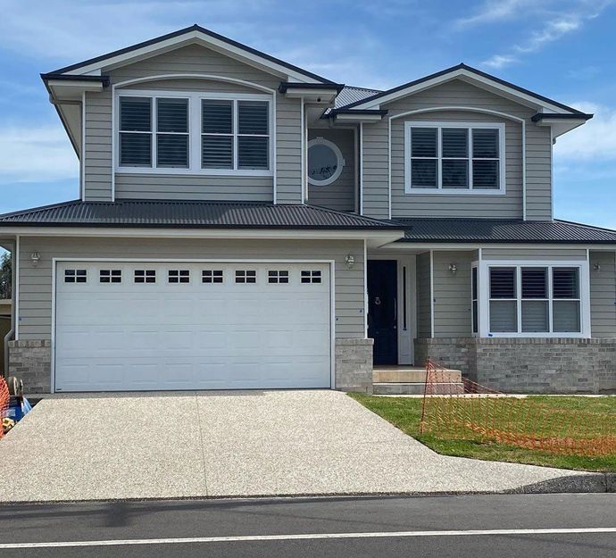 White garage door in a brick building. Gravel driveway.