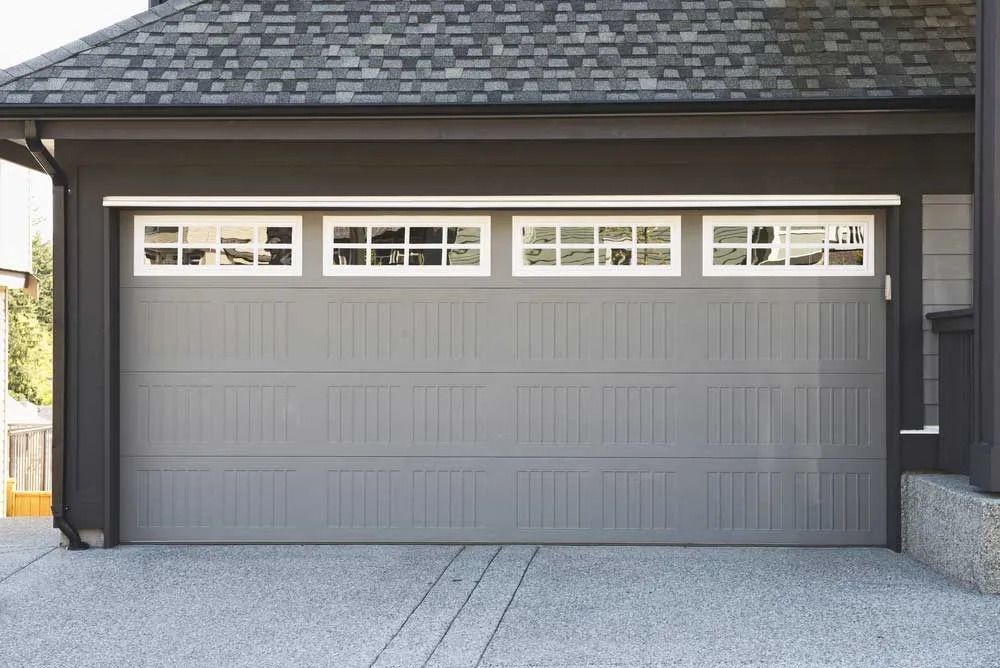 Gray garage door with window panels and concrete driveway.