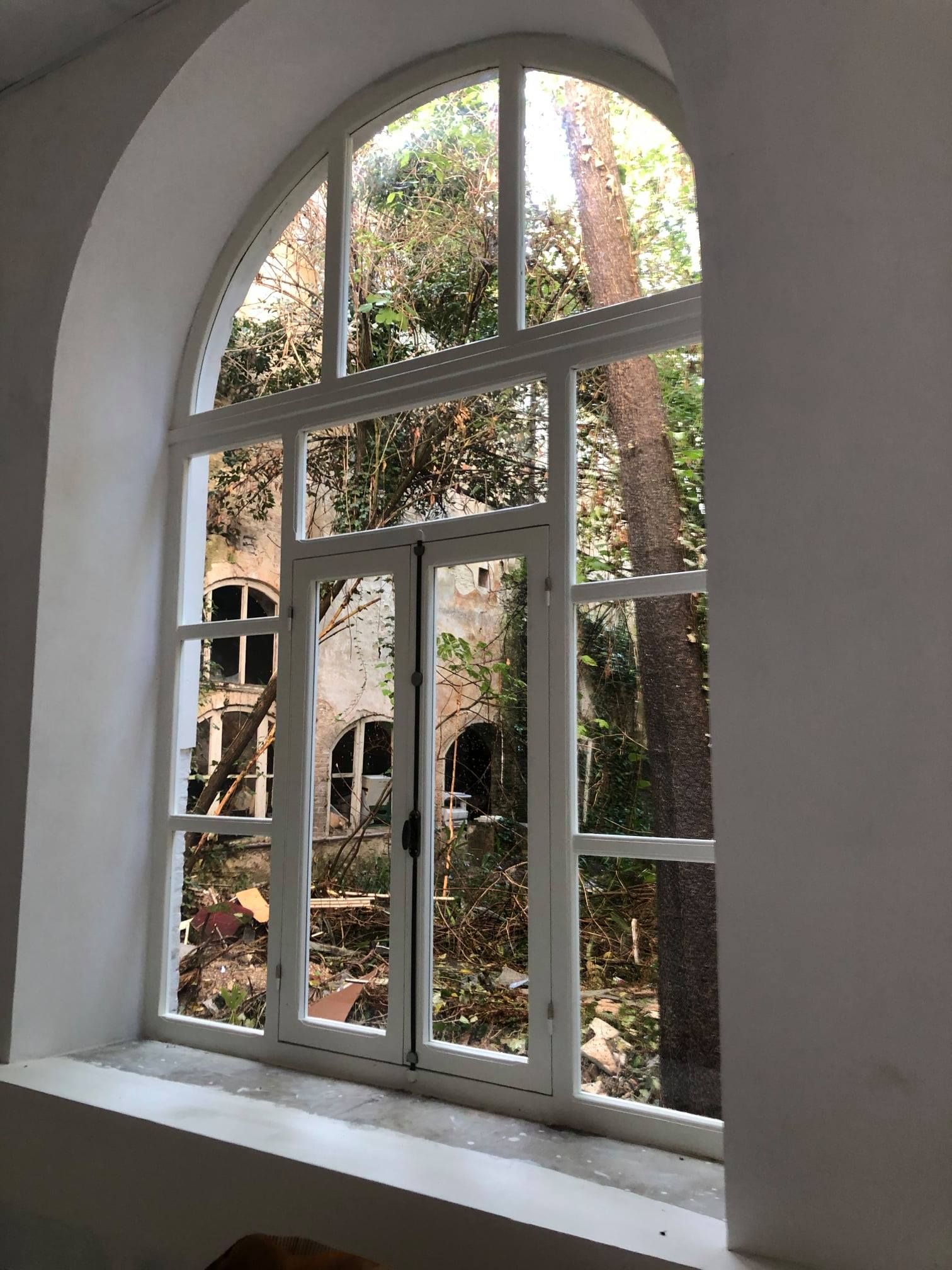 Una grande finestra ad arco con vista sul giardino.