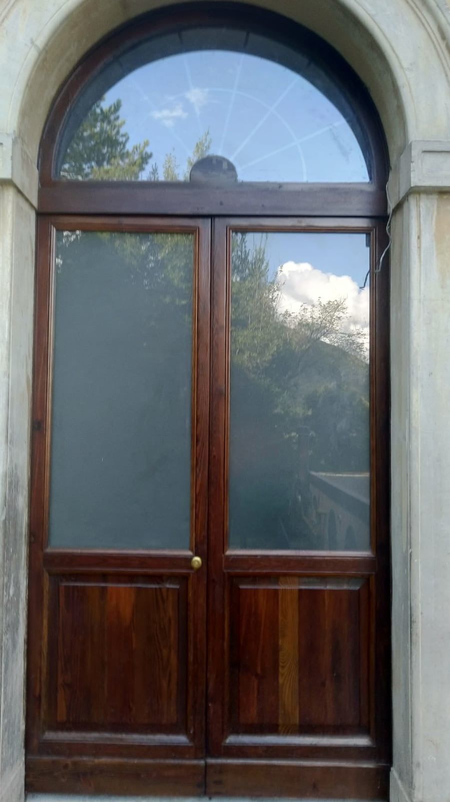 Una porta di legno con una finestra rotonda in cima.