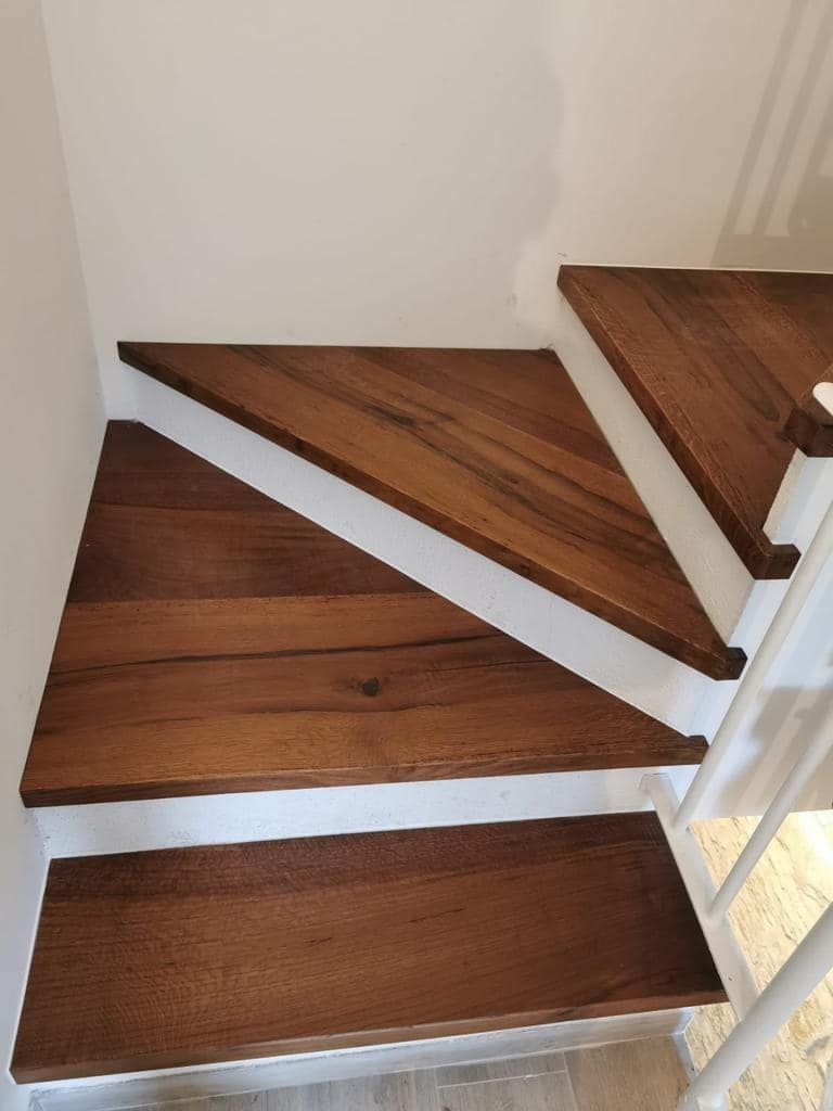 Primo piano di una scala in legno con ringhiera bianca.