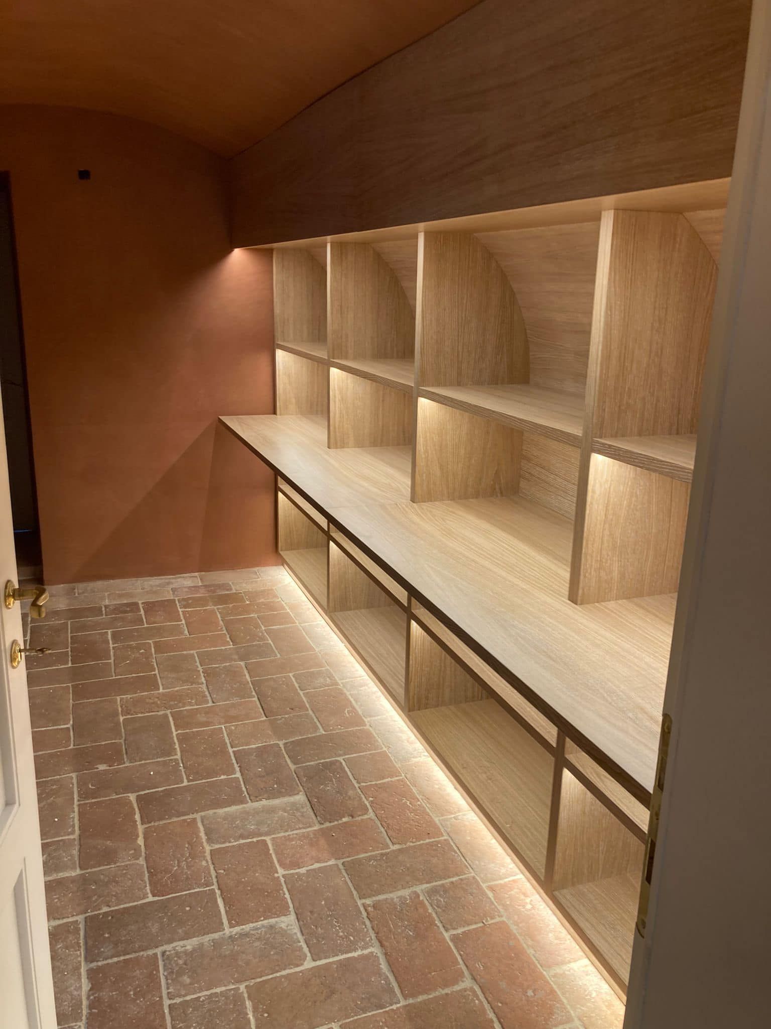 Una stanza con scaffali di legno e pavimento in mattoni.