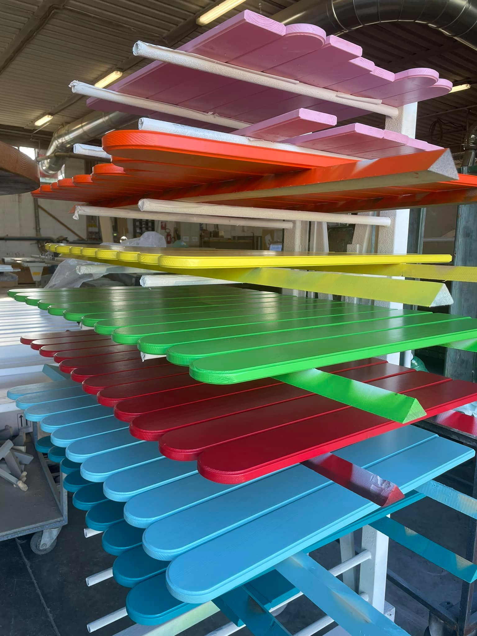 Un mucchio di assi di legno colorate sono accatastate l'una sull'altra su uno scaffale.