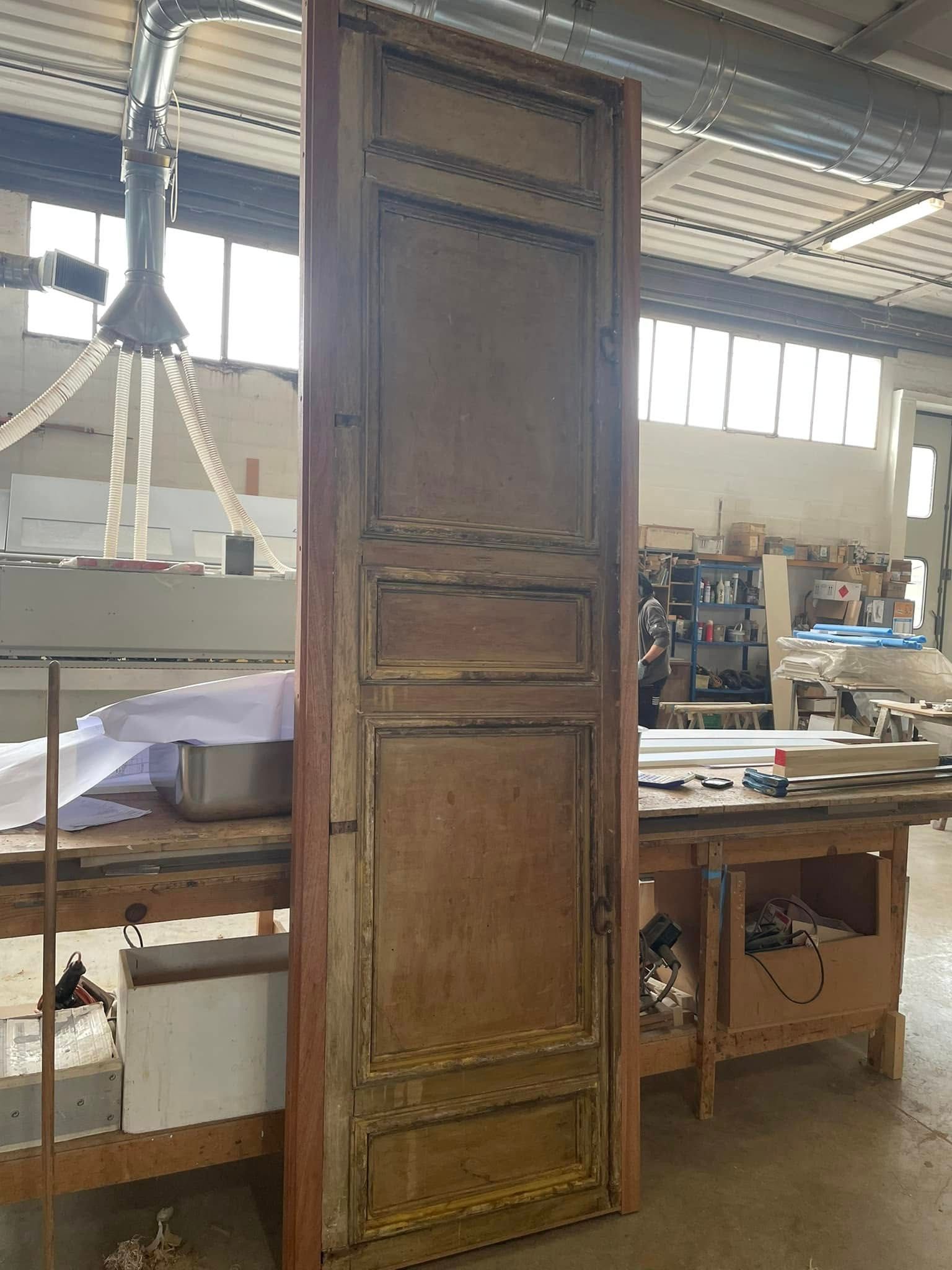 Una porta di legno è appoggiata su un tavolo di legno in un laboratorio.