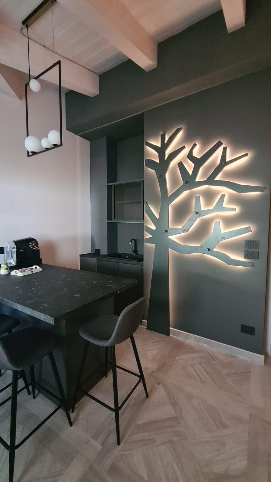 Una cucina con tavolo e sedie e un albero sul muro.