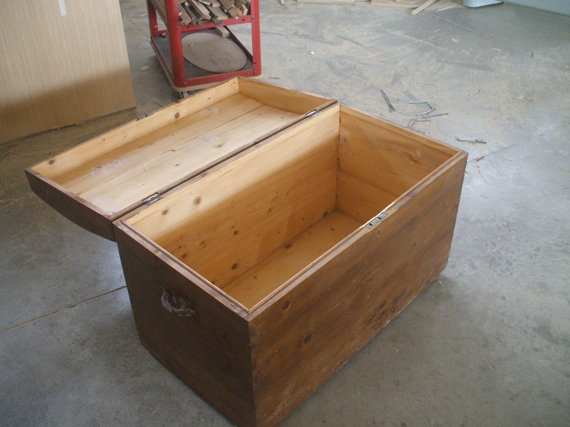 Un baule di legno con il coperchio aperto su un pavimento di cemento