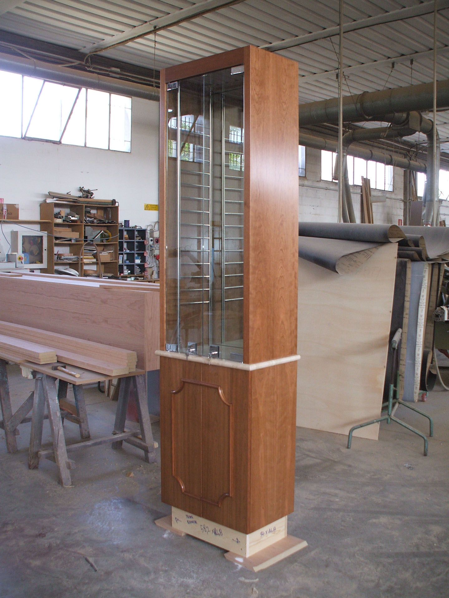 In una stanza c'è un mobiletto di legno con ante in vetro.