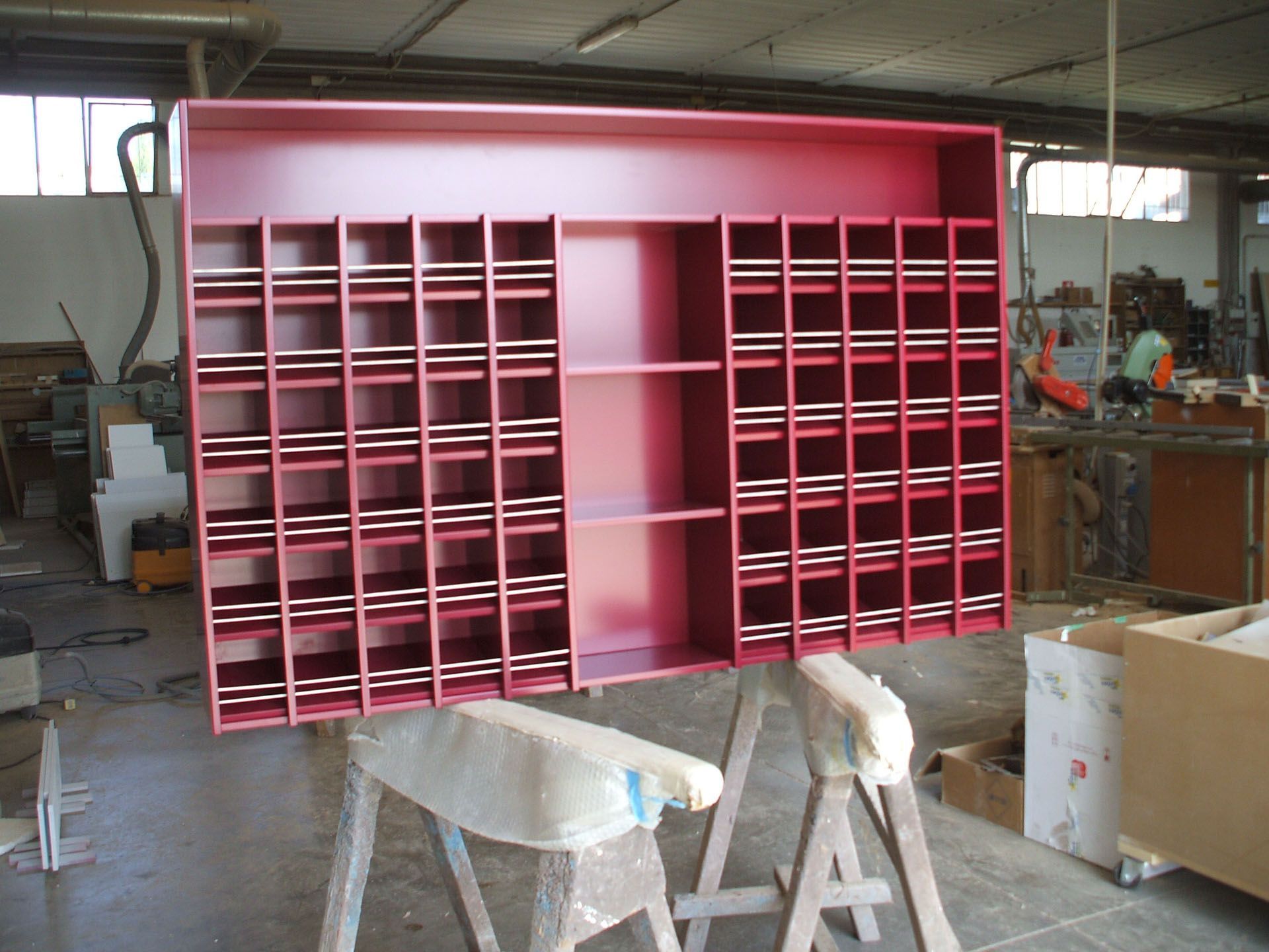 Un grande scaffale rosso è appoggiato su un supporto di legno
