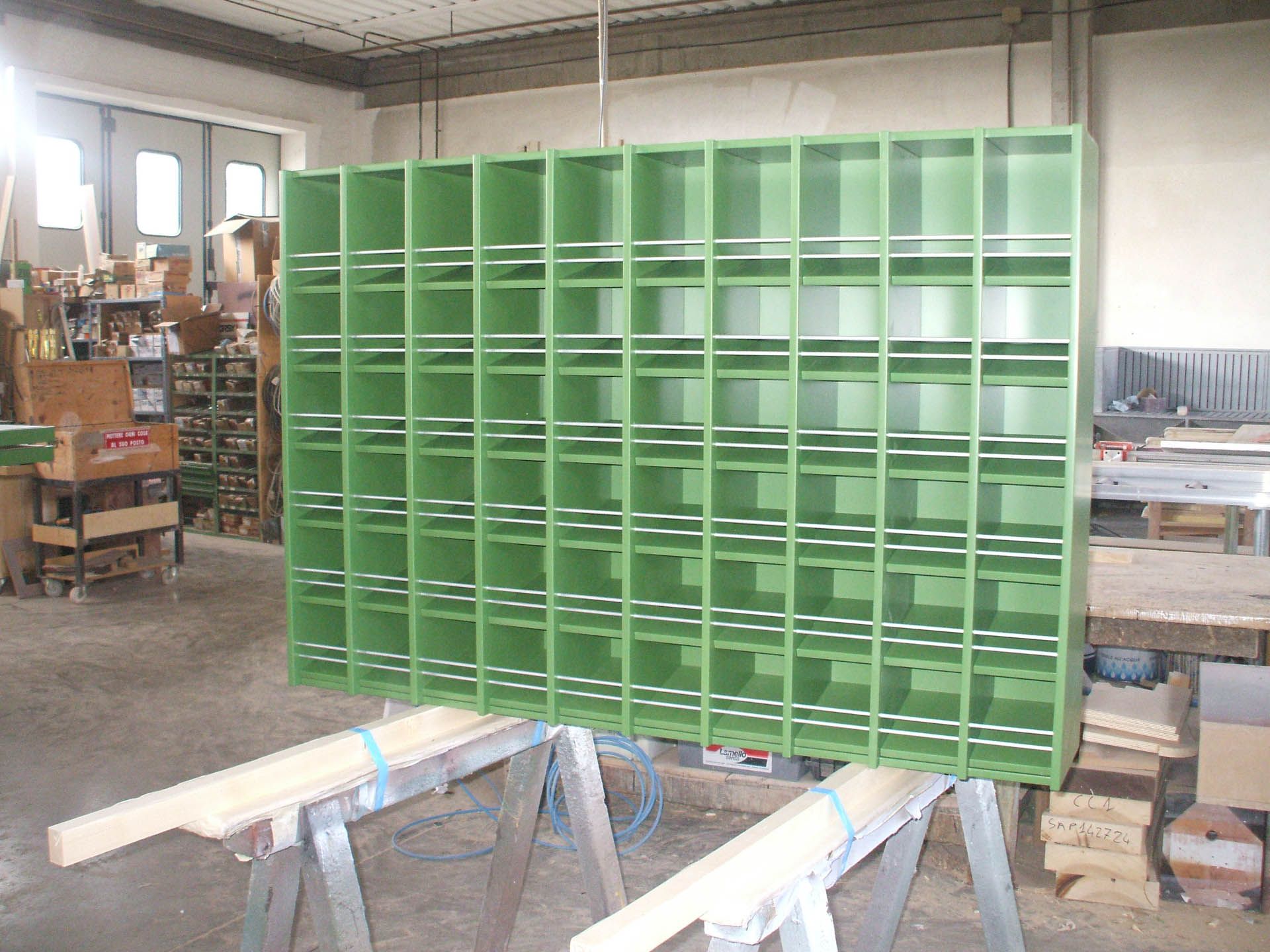Uno scaffale verde è appoggiato su un tavolo di legno in un laboratorio.