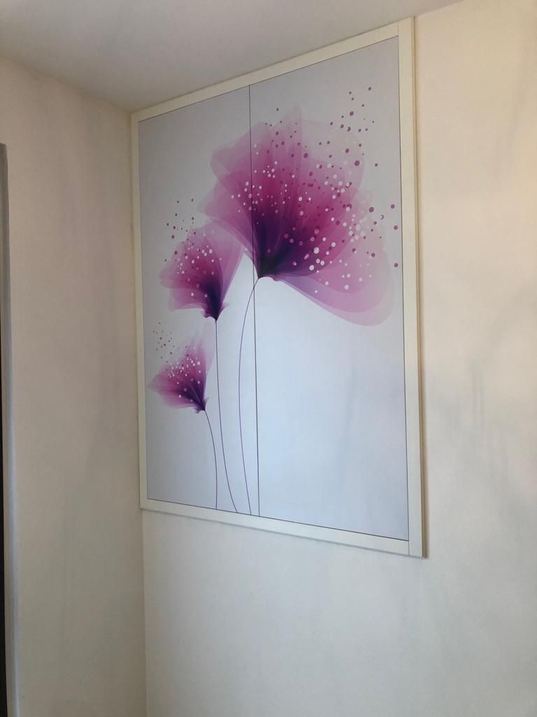 Un'immagine di fiori viola su un muro bianco
