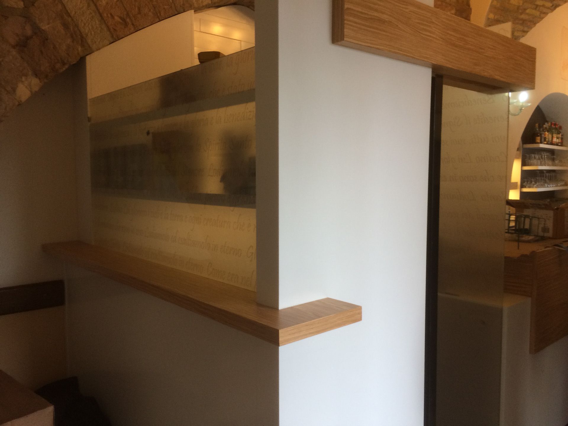 Un angolo di una stanza con una mensola di legno e una porta scorrevole in vetro.