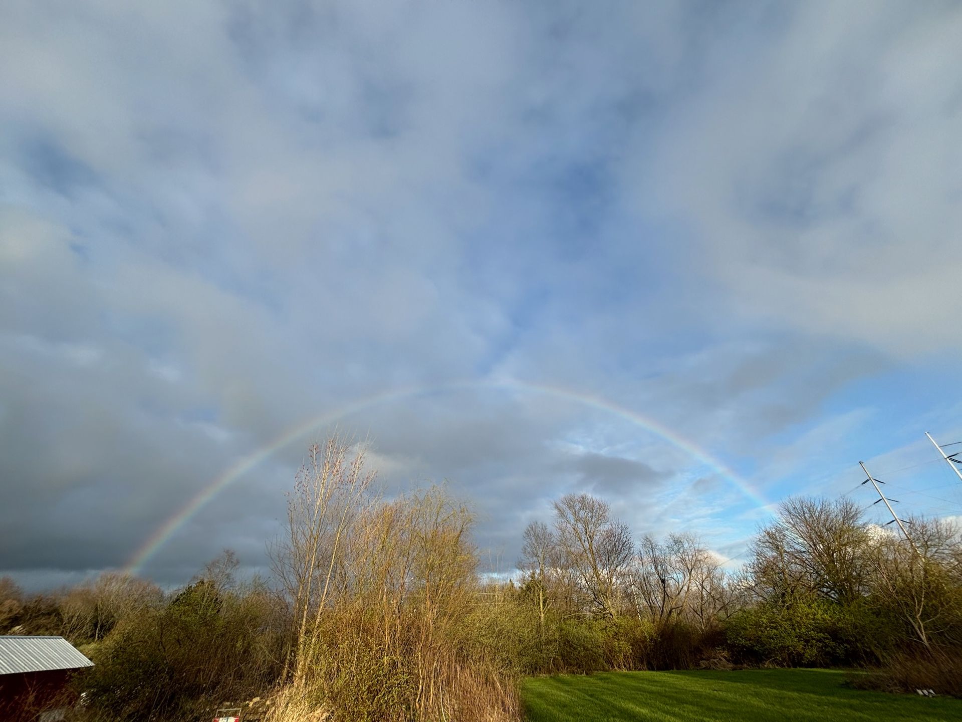A rainbow is visible in the sky over a field