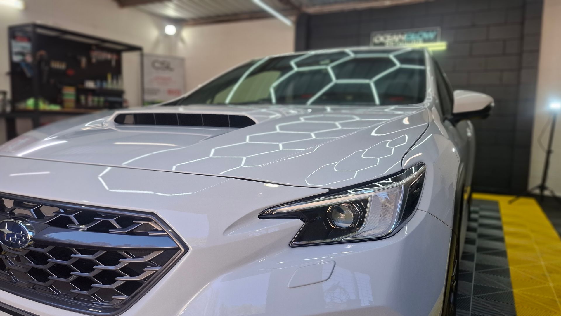 A white car with a honeycomb grille is parked in a garage. – Ocean Glow Car Detailing in Long Jetty NSW