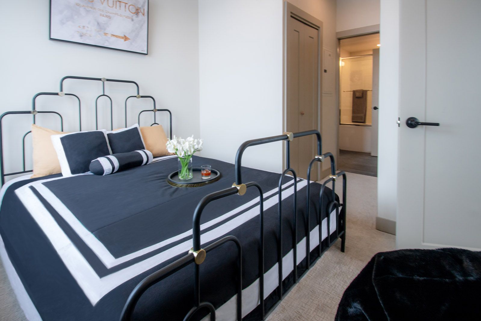 A bedroom with a black and white bed and a picture on the wall.