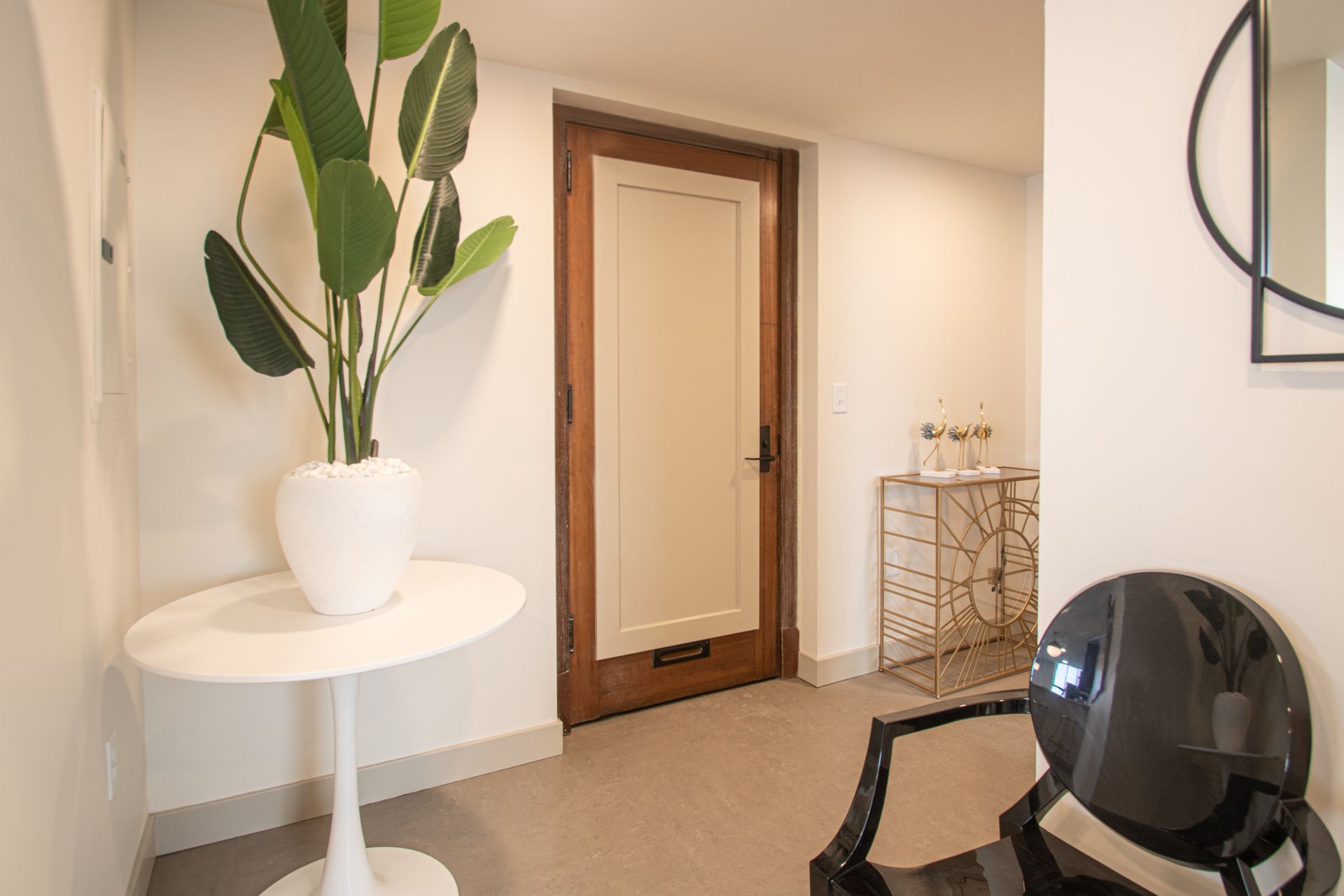 A white table with a plant on it in a hallway next to a door.